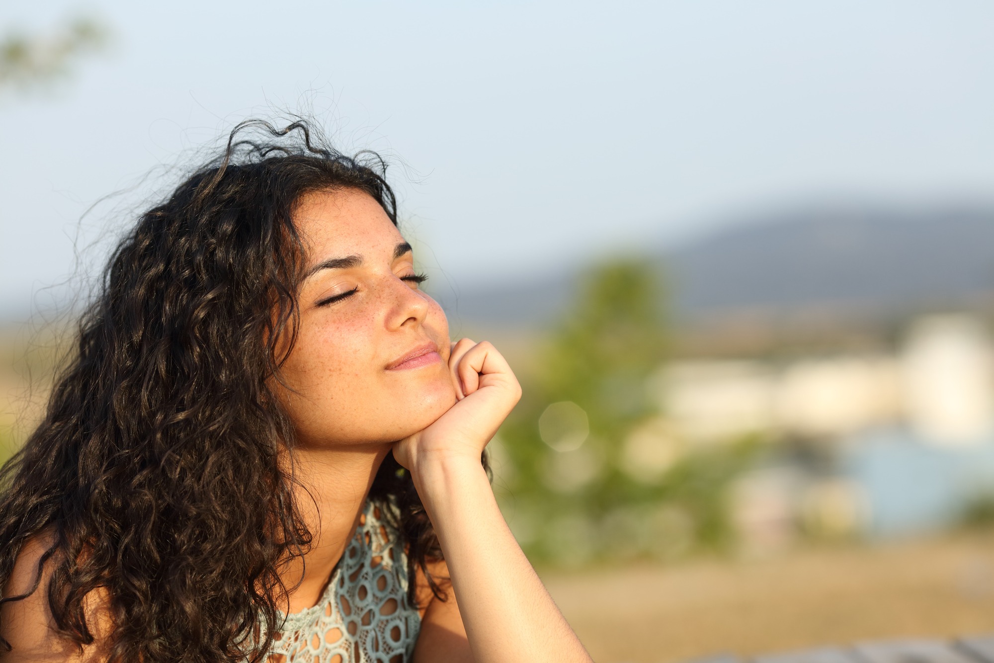 Woman relaxing and enjoying the sun in a warmth park at sunset